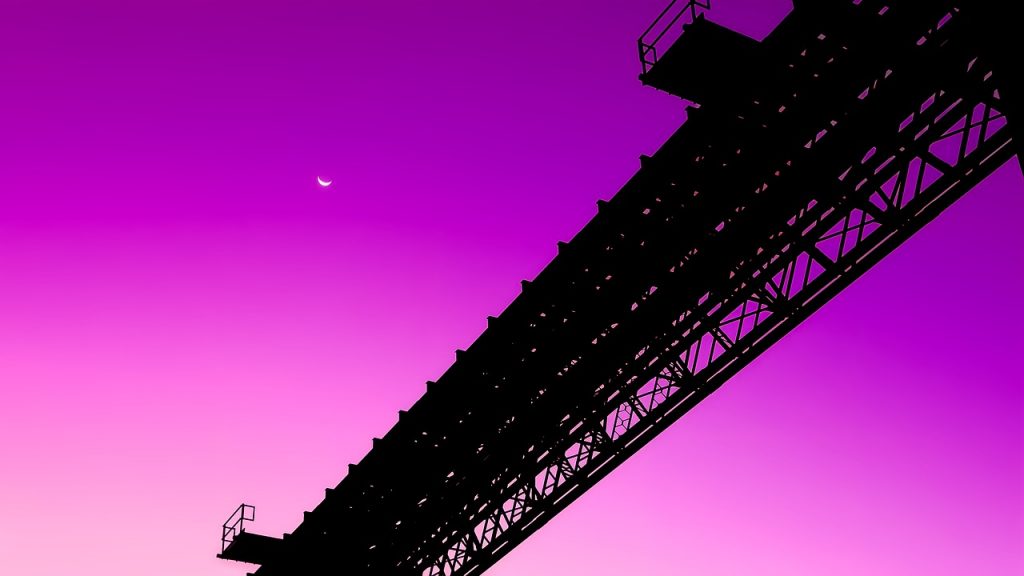 Kuvassa on rautatiesilta violettia taivasta vasten. 